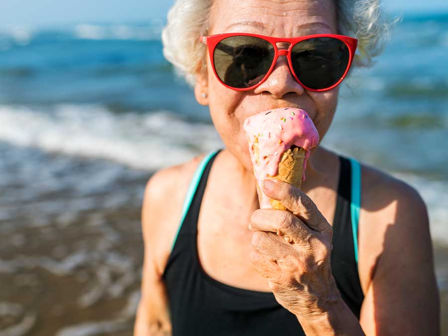 Senior lady eating ice cream on the beach