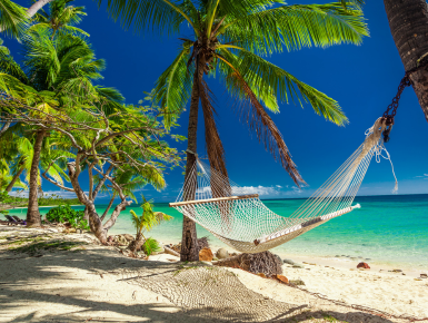 Hammock on beach with clear water in background