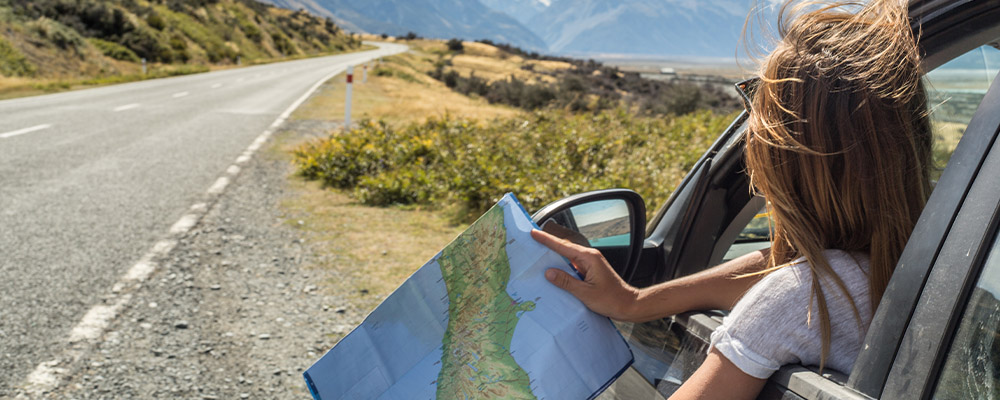 Holding map out window of car