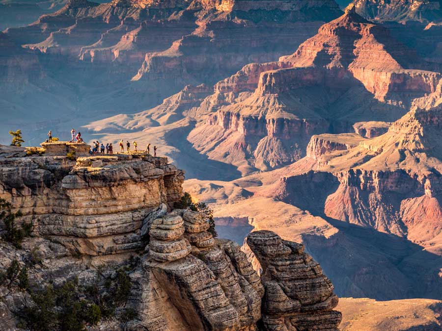 A group of hikers  watching the sun set over  Grand Canyon National Park, Arizona, USA